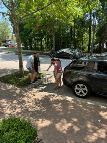 A group of people standing next to a car  Description automatically generated