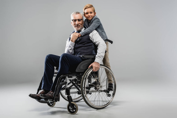 stock-photo-smiling-boy-hugging-grandfather-wheelchair-while-looking-camera-together-grey.jpeg